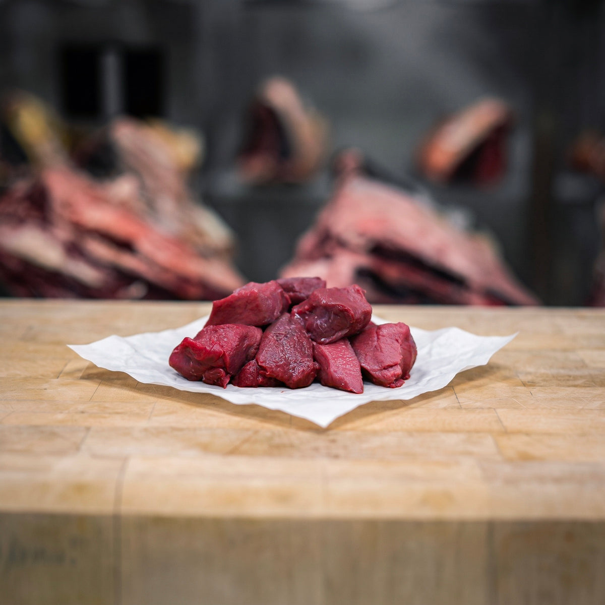 Morceaux crus de biche et cerf pour civet, coupés dans l’épaule et le collier, en tas sur un billot en bois